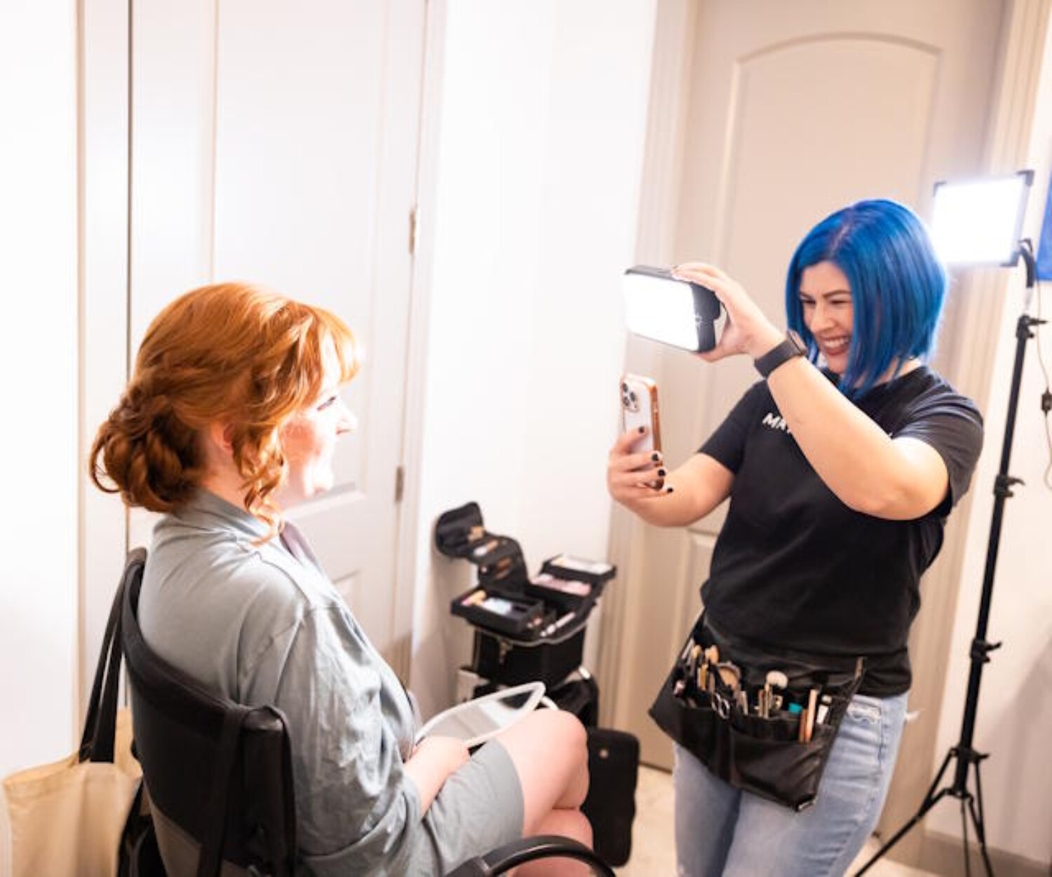 Makeup By Diana adjusting lighting and capturing a beauty photo of a bride during the getting‑ready process in an Arizona bridal suite.