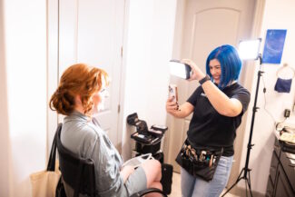 Makeup By Diana adjusting lighting and capturing a beauty photo of a bride during the getting‑ready process in an Arizona bridal suite.